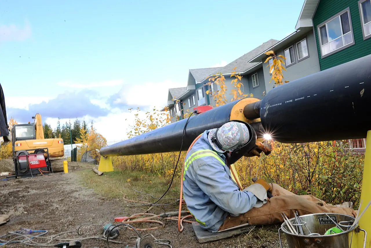 A welder joining pipeline sections in the field