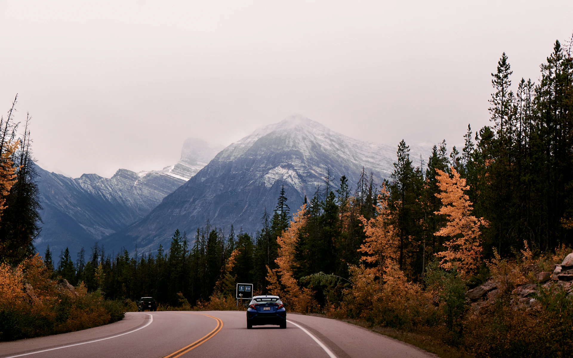Car on a mountain road into the Rockies in autumn
